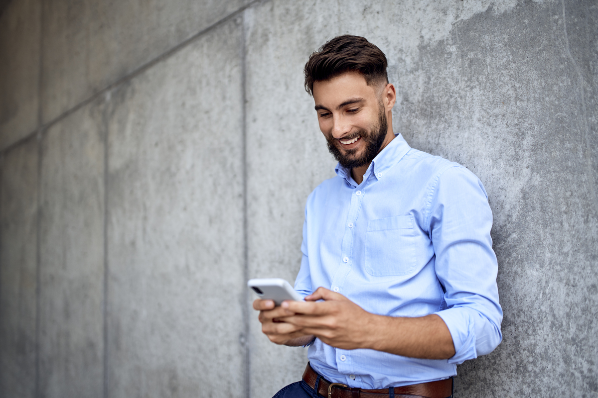 Young businessman smiling while texting on smartphone in the city
