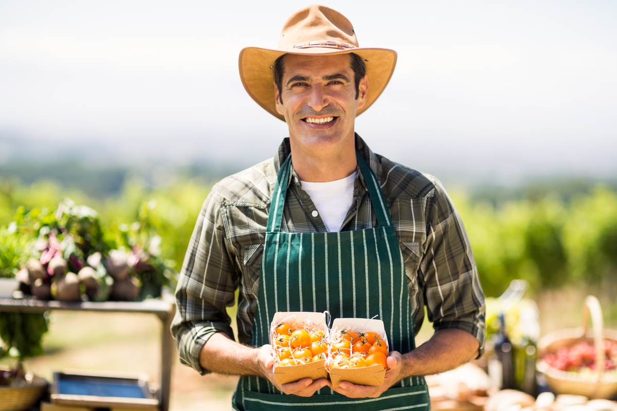 Portrait,Of,A,Smiling,Farmer,Holding,Box,Of,Fruit,At