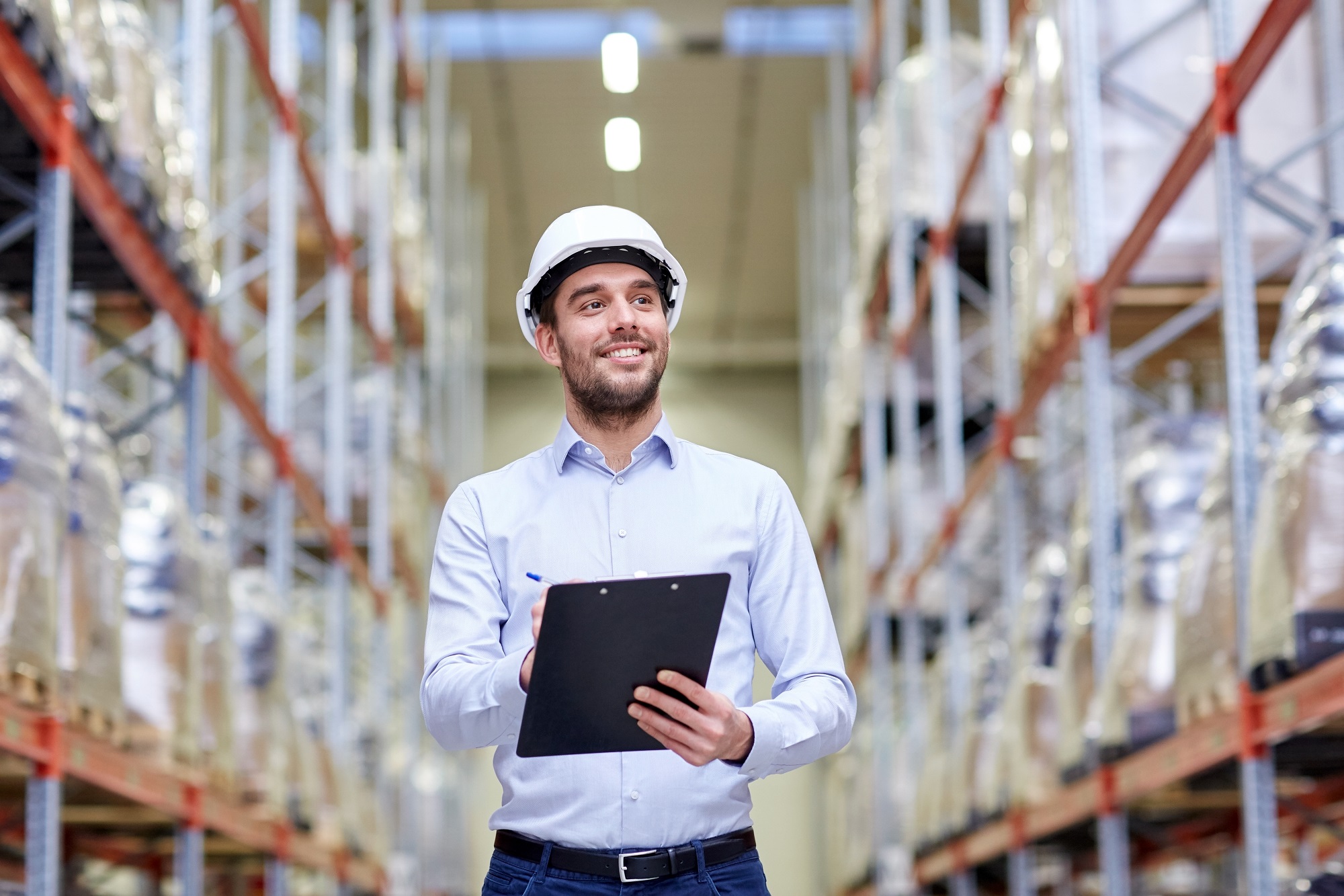 happy businessman with clipboard at warehouse