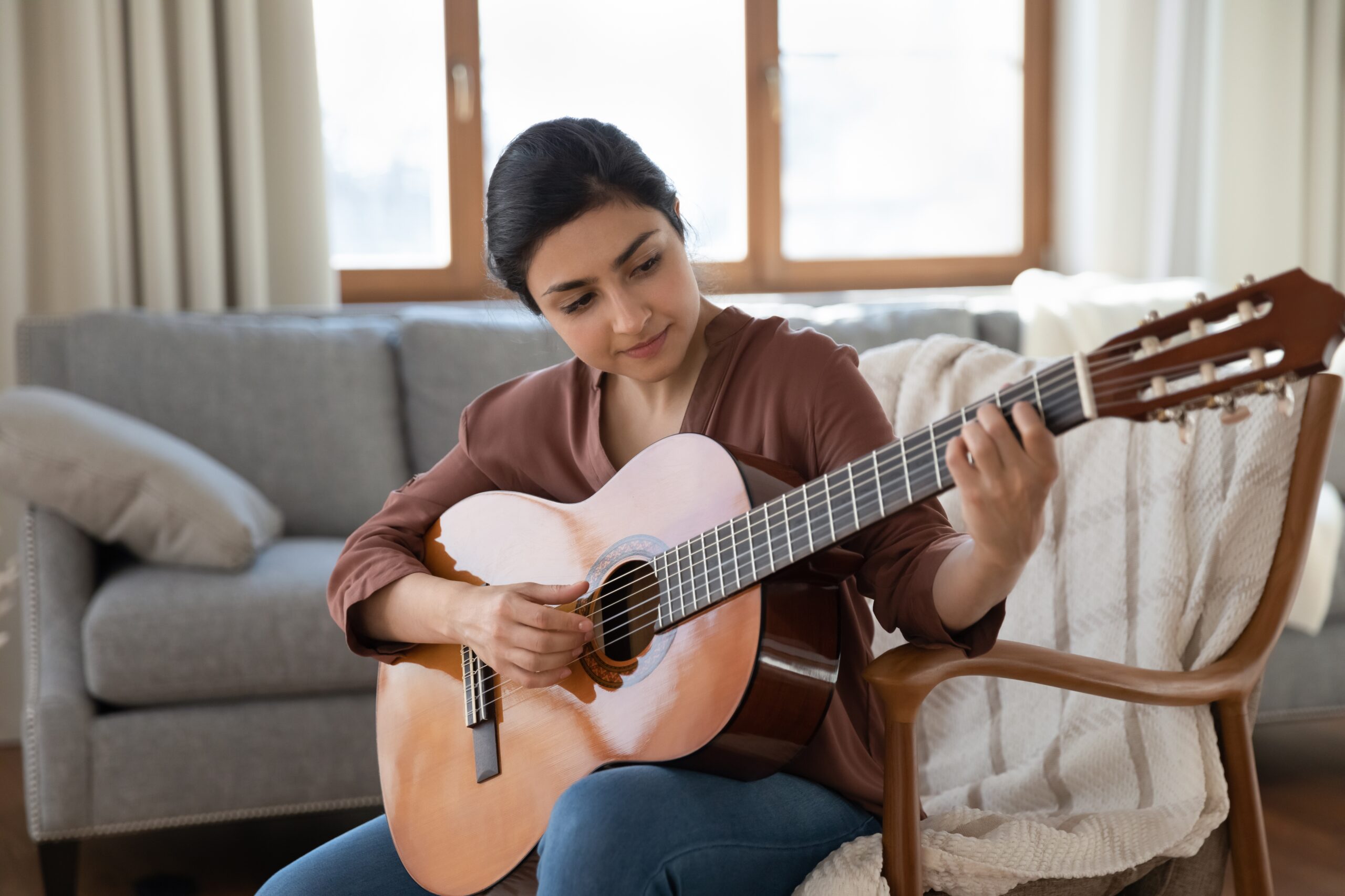 Talented,Concentrated,Young,Indian,Woman,Holding,Guitar,In,Hands,,Practicing