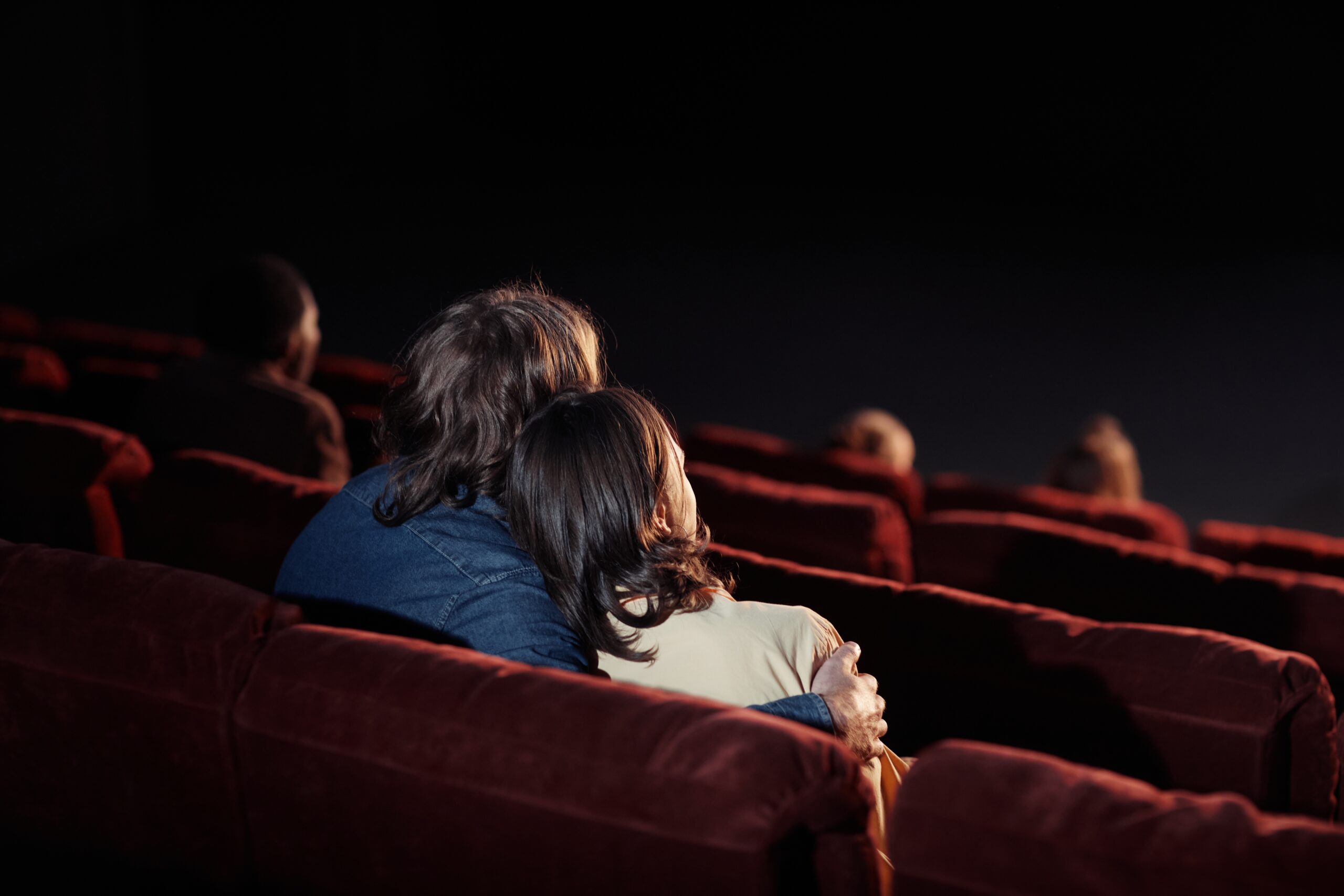 Rear,View,Of,Affectionate,Couple,Embracing,While,Watching,Movie,On